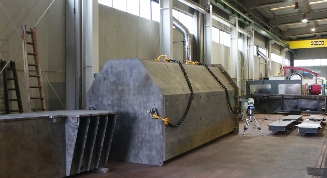 Gran soporte mecanizado posado en el suelo de las instalaciones de LAMUCE y con cadenas de transporte para puente grúa de 40t. Vista lateral izquierda del soporte