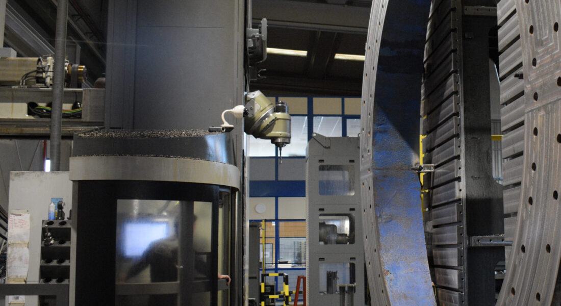 Anillo eólico presentado para continuar su mecanizado en la fresadora Zayer Kairos 12000 en las instalaciones de LAMUCE. Vista lateral y a la izquierda de la imagen la cabina de control de la fresadora con un técnico dentro trabajando