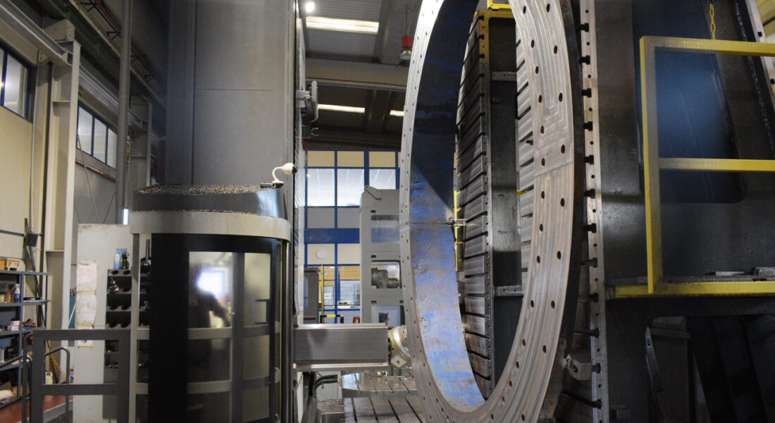 Anillo eólico presentado para continuar su mecanizado en la fresadora Zayer Kairos 12000 en las instalaciones de LAMUCE. Vista lateral y a la izquierda de la imagen la cabina de control de la fresadora con un operario dentro trabajando