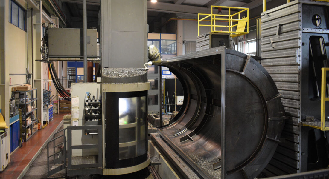 Estructura de horno de grandes dimensiones siendo mecanizada en la fresadora Zayer Kairos 12000. Vista lateral derecha completa de la pieza y a la izquierda el operario en la cabina de control de la fresadora